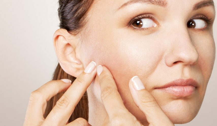 white women picking at a spot on her face