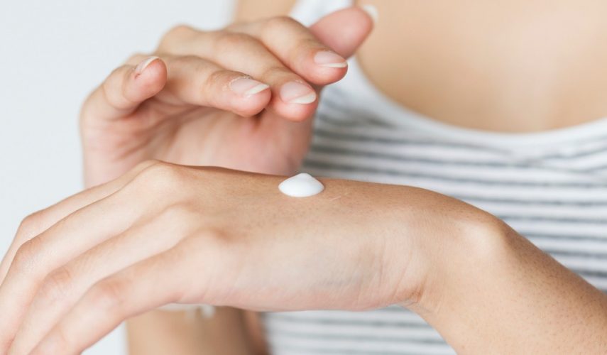 woman carrying out her beauty regime by applying hand cream to her hands