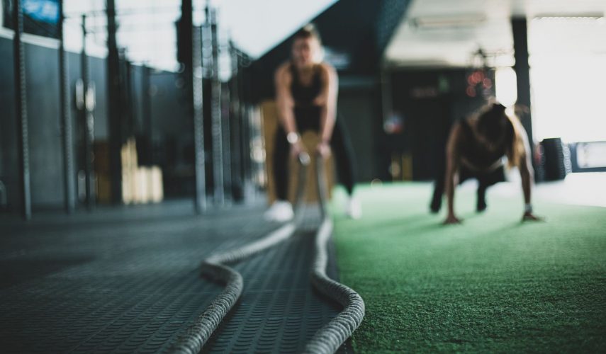 young women at the gym working out using battle ropes