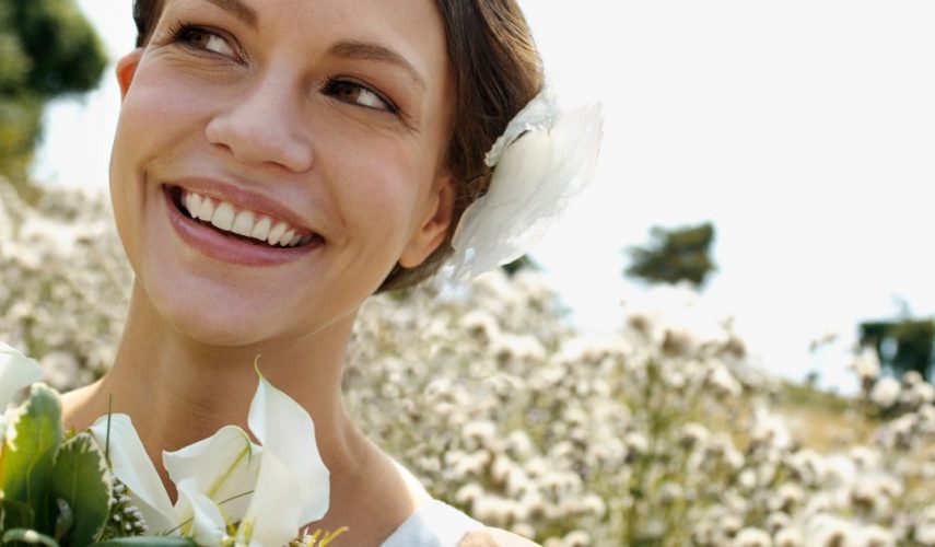 beautiful brunette women in a wedding dress surrounded by white flowers