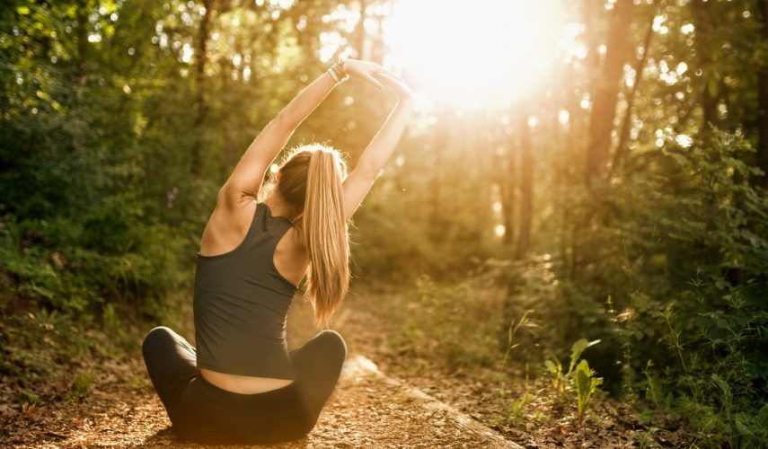 beautiful blonde lady wearing gym clothes and practising yoga outside