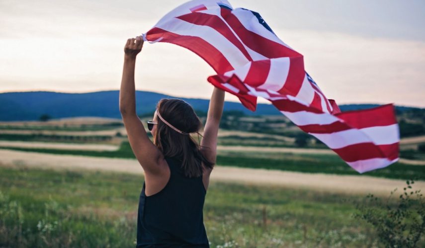 brunette lady holding an American flag in the wind