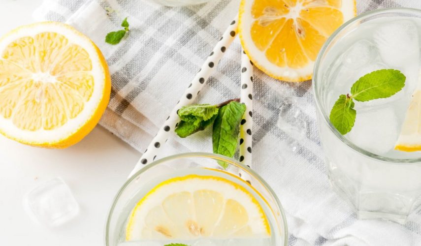 cut lemons next to a glass of refreshing homemade lemonade