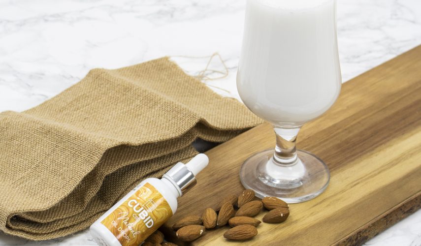glass of almond milk, almond nuts and CBD oil drops