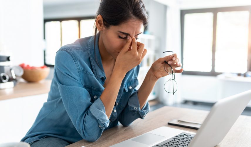 Stressed business woman working from home on laptop looking worried, tired and overwhelmed