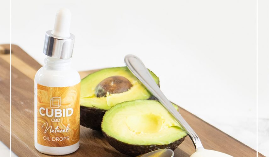 healthy foods used to create a natural CBD face mask - avocado, spoon of yoghurt and honey, CBD oil drops