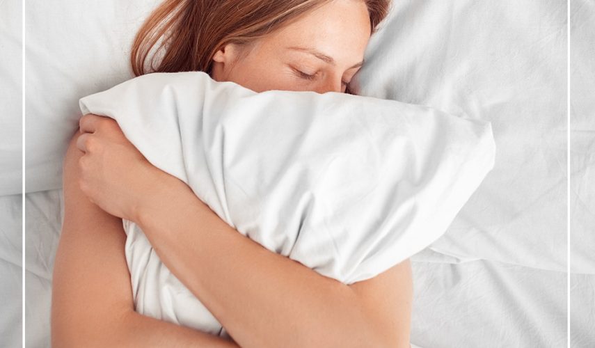 women cuddling a pillow in bed trying to get to sleep