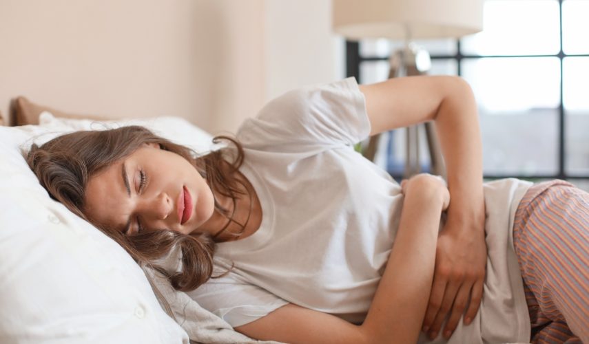 women lying in bed suffering with period pains and period cramps